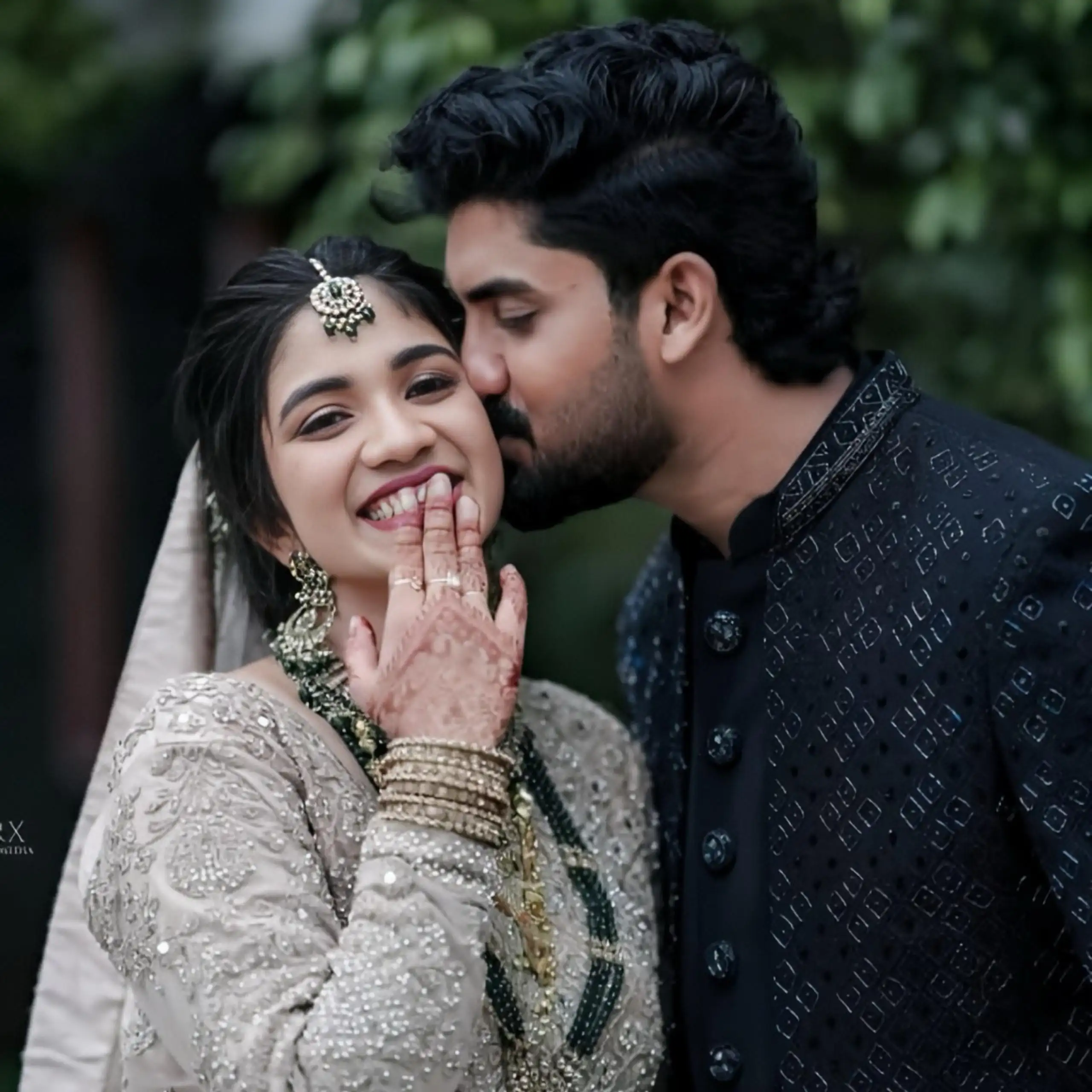 Bride blushes and smiles as the groom kisses her, captured by the best wedding photographer in Malappuram