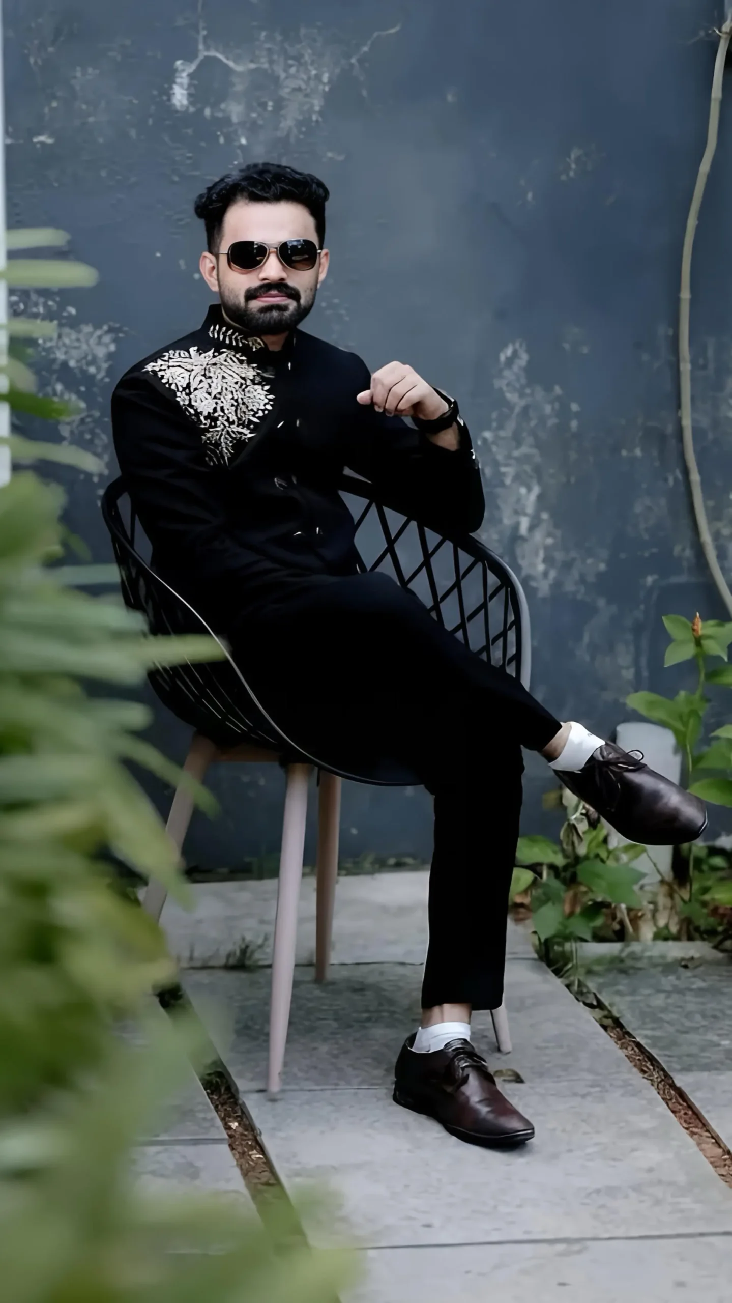 Handsome groom wearing black coat and pant with cooling glass, captured by the best wedding photographer in Malappuram