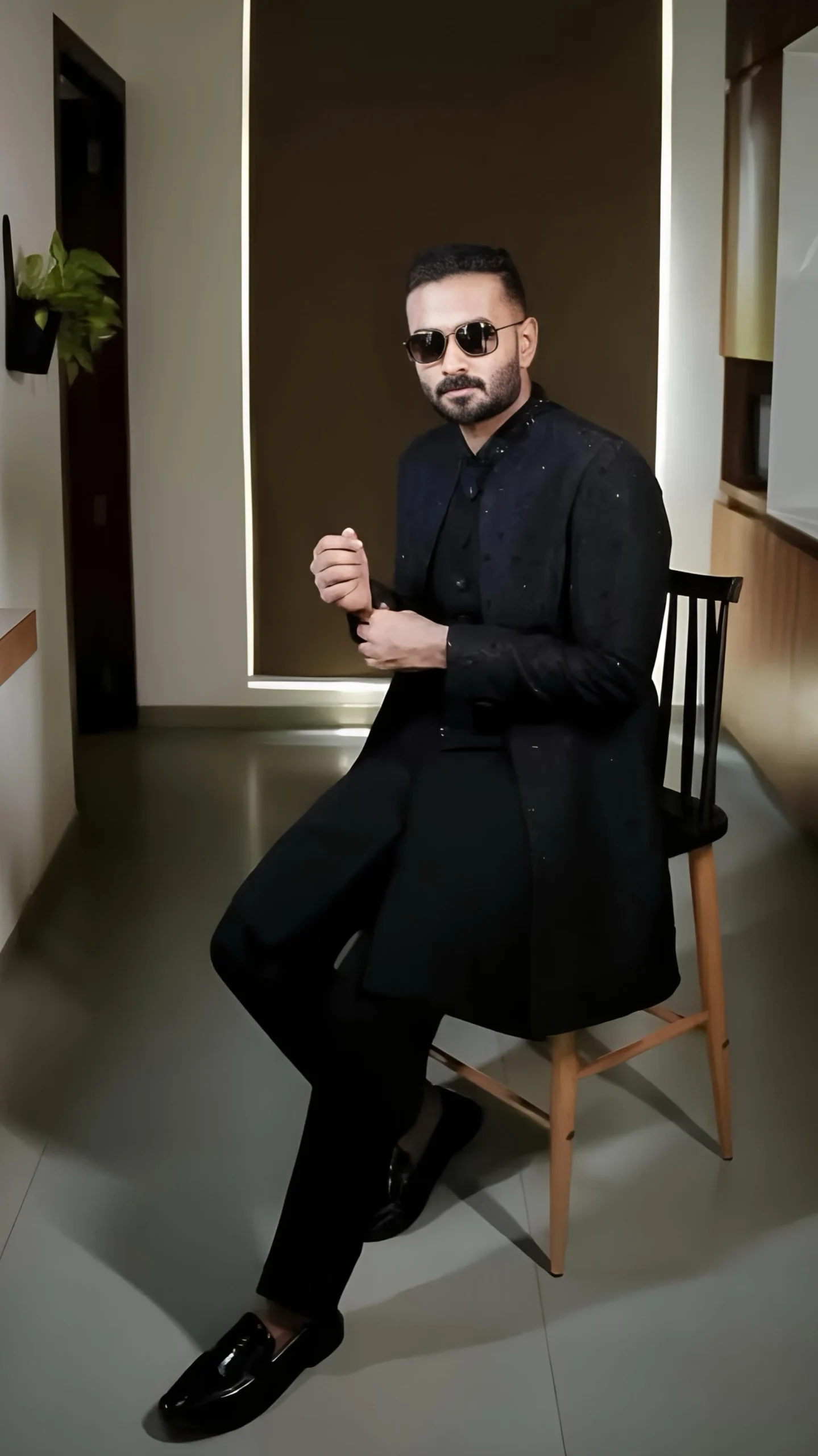 Handsome groom wearing black coat and pant with cooling glass, captured by the best wedding photographer in Malappuram