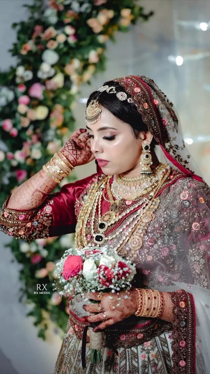 Bride in a red gown holding a small flower bouquet, highlighting her jewelry, captured by the best wedding photographer in Malappuram.